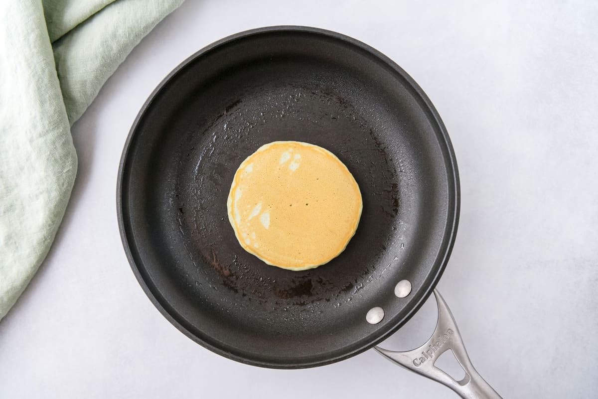 Pancake cuit dans une poêle noire.