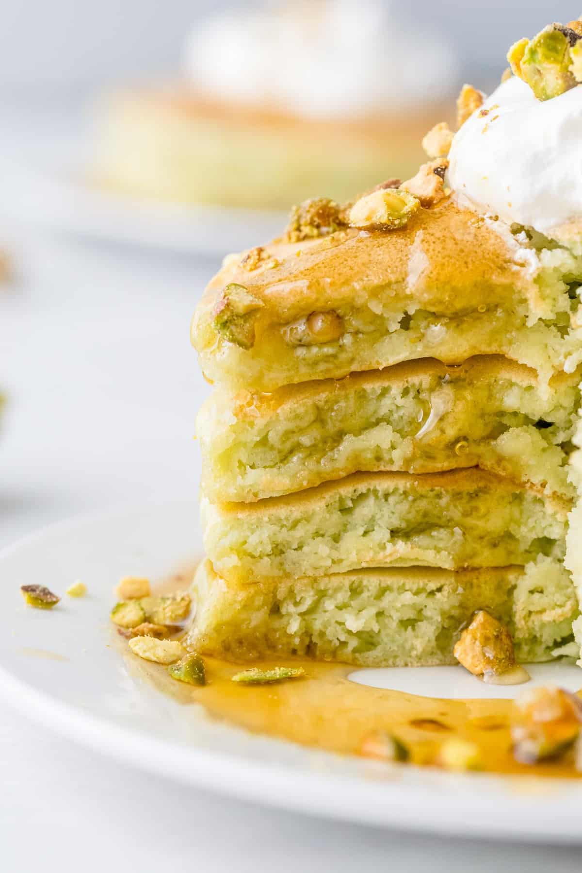 Gros plan sur du sirop dégoulinant sur une pile de pancakes coupés.