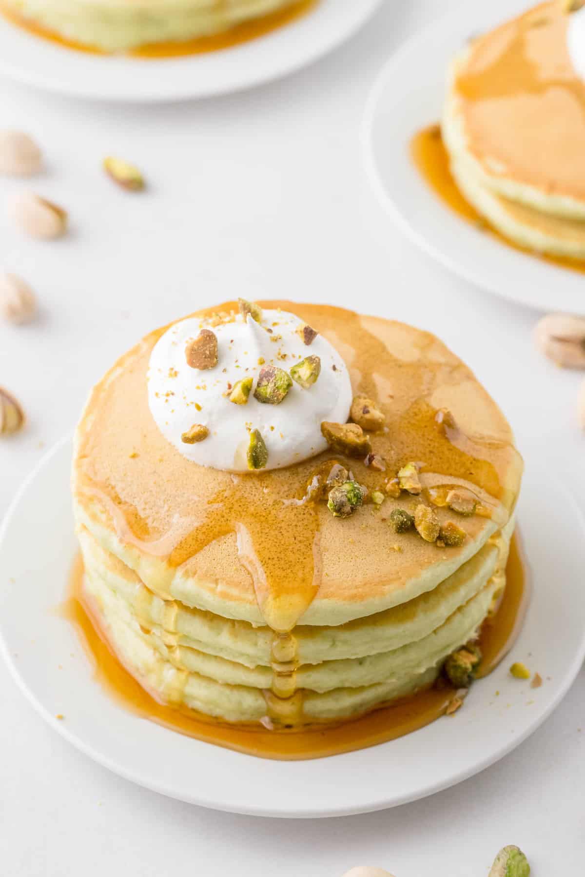 Pancakes garnis de sirop, de crème fouettée et de pistaches.