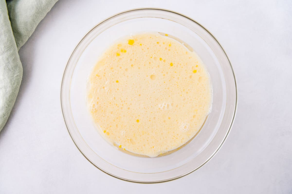 Œufs et lait dans un bol de mélange en verre.
