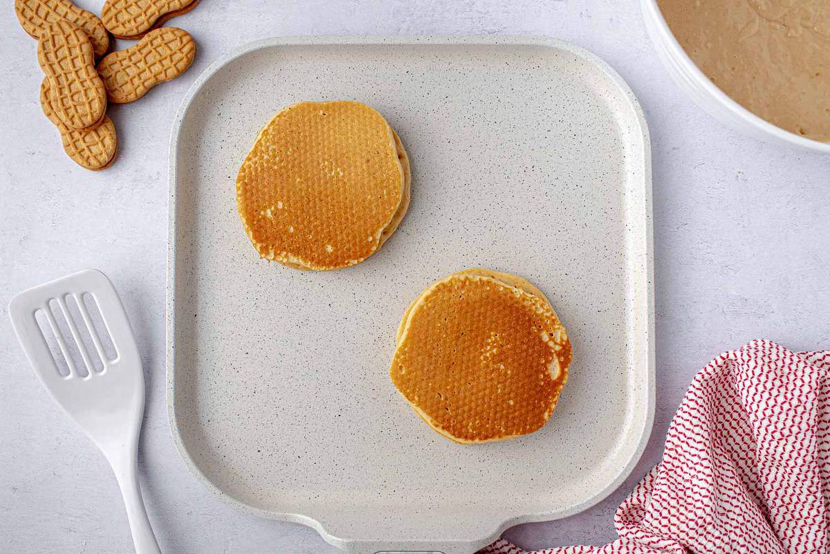 Pancakes cuits dans une poêle blanche.