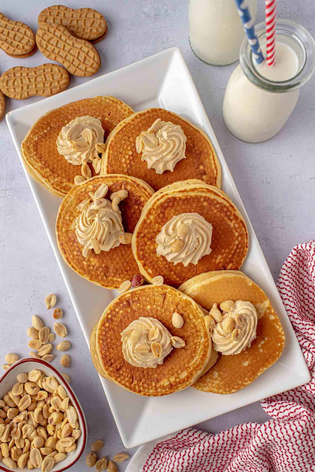 Pancakes sur un plat rectangulaire avec de la crème fouettée au beurre d'arachide.