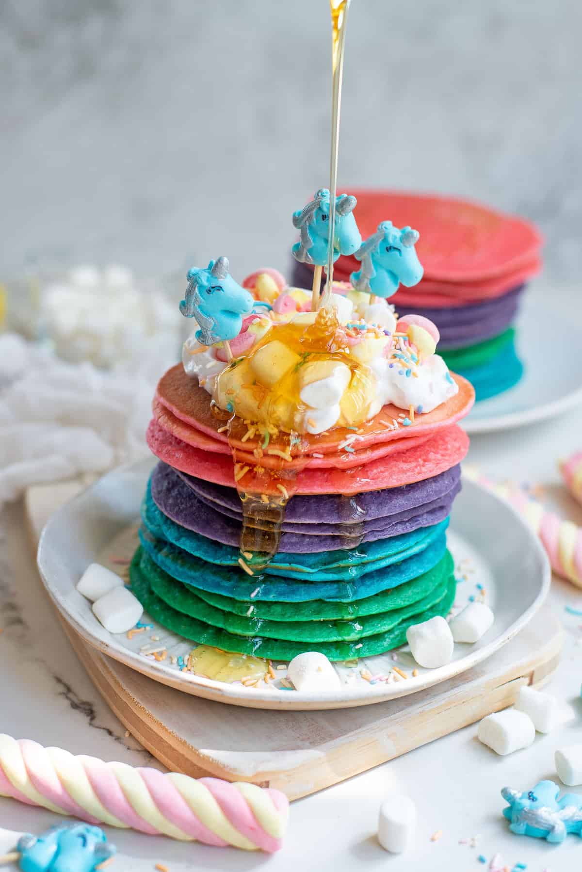 Pile de pancakes licorne avec du miel versé dessus.