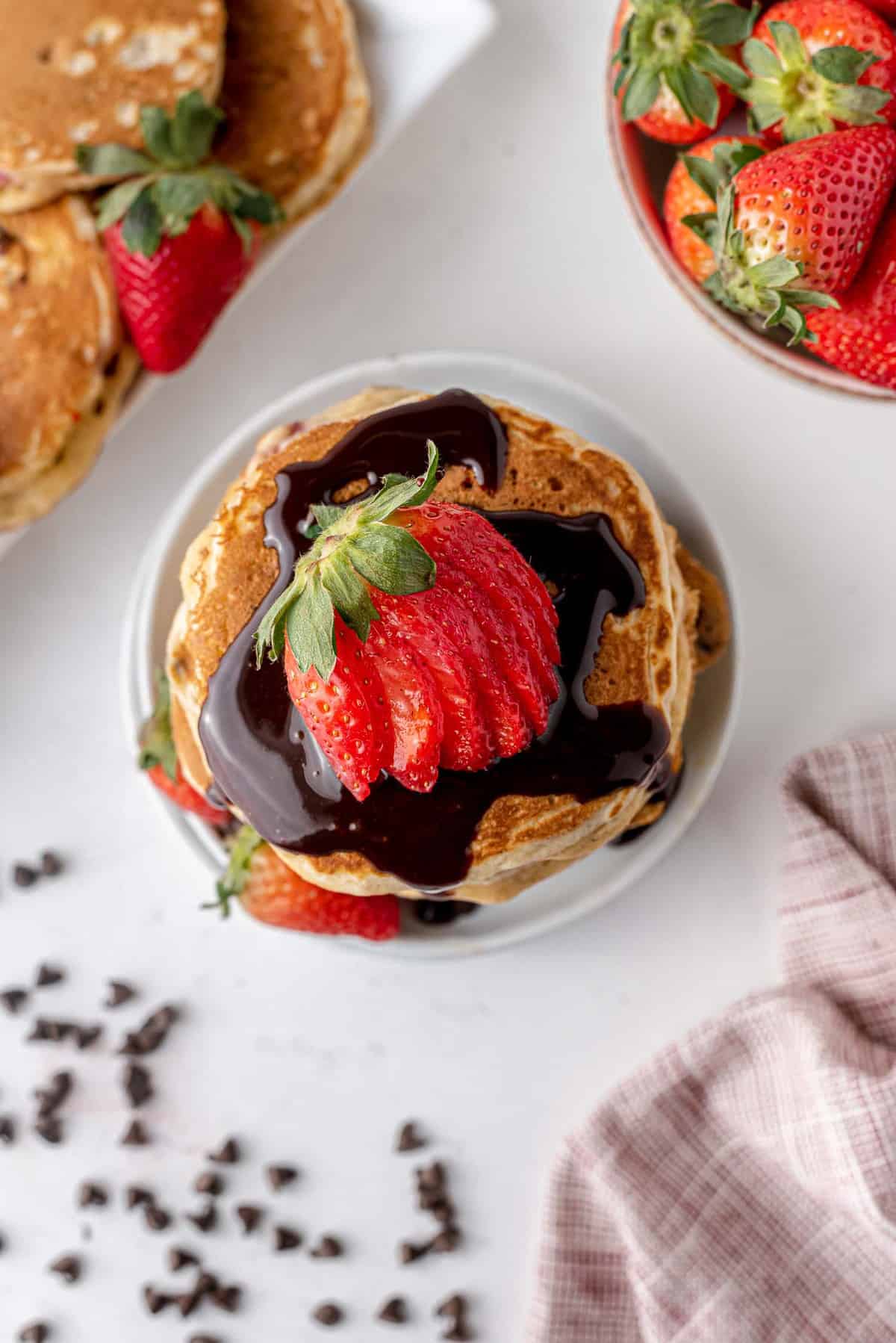 Vue aérienne d'une pile de pancakes avec du sirop au chocolat et des fraises.