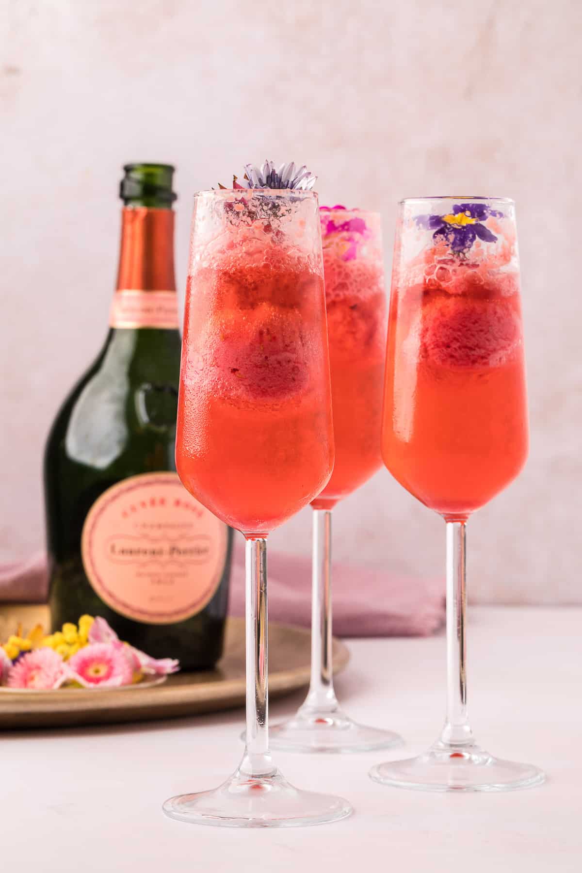 Trois verres de floats au champagne avec des fleurs comestibles.