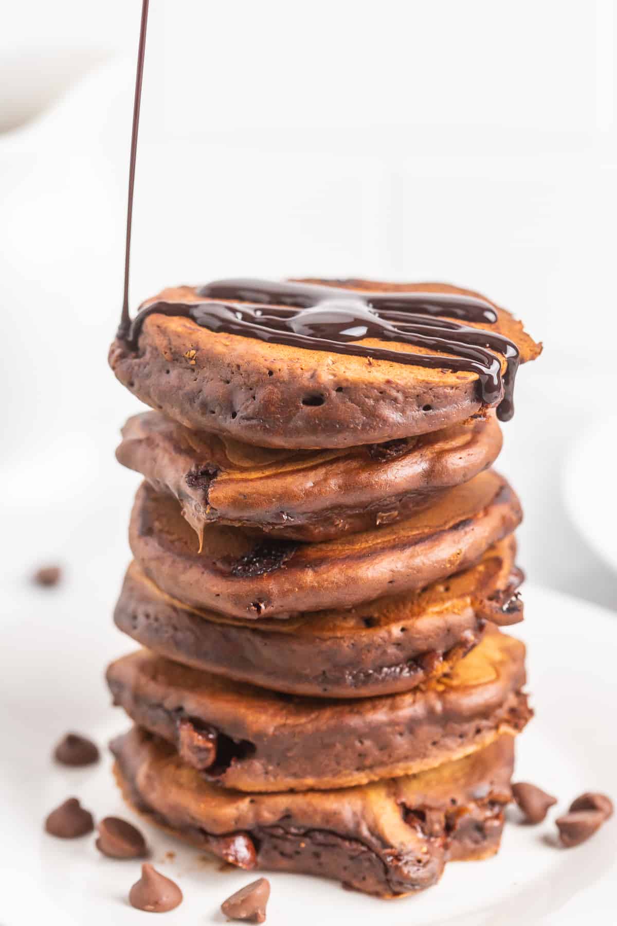 Du sirop versé sur des pancakes au chocolat.