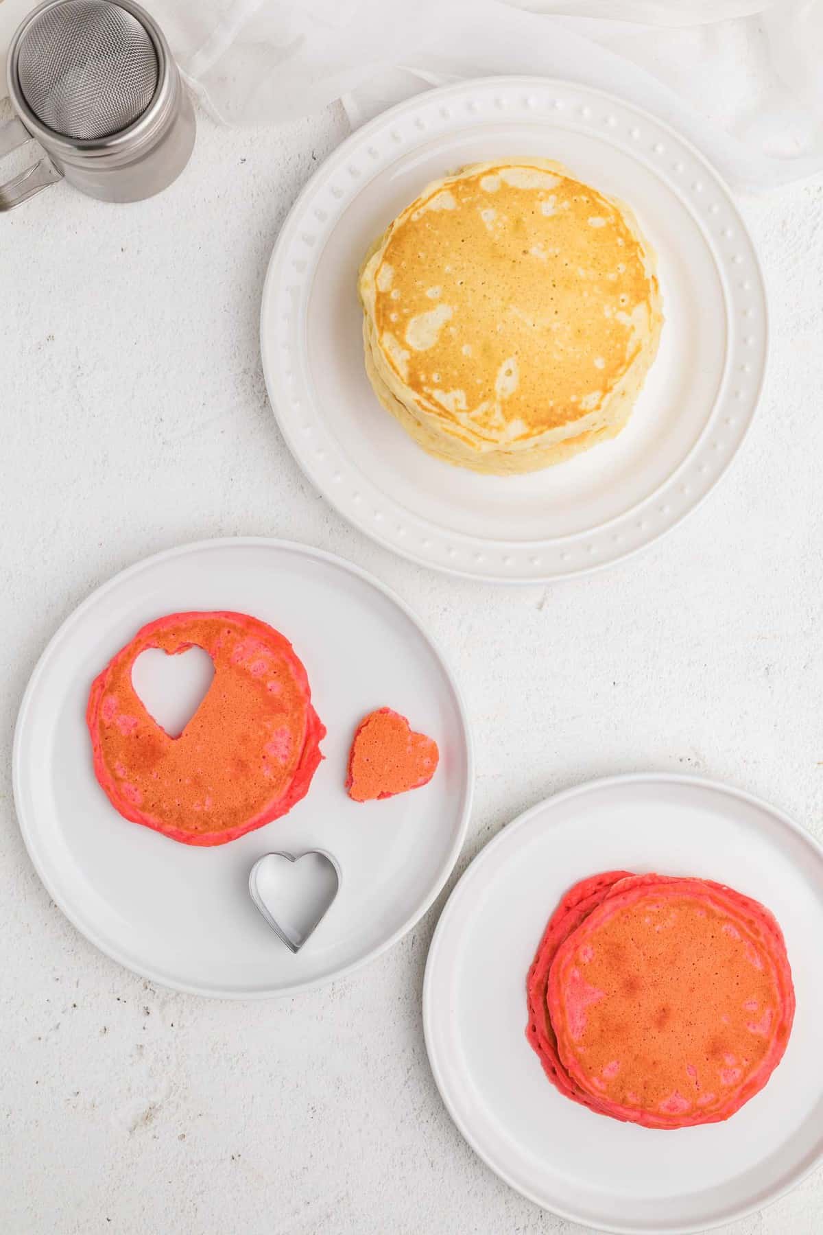 Emporte-pièce en forme de cœur découpant un cœur dans un pancake rouge.