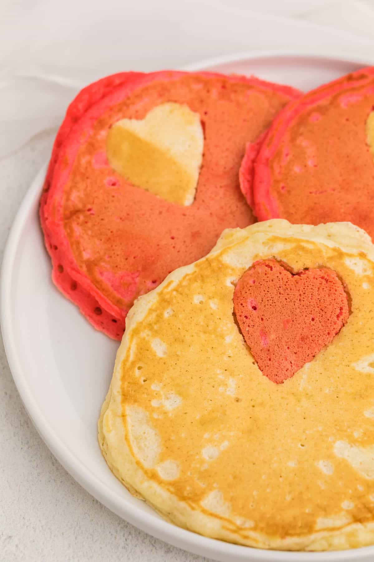 Gros plan de pancakes avec une forme de cœur colorée contrastante.