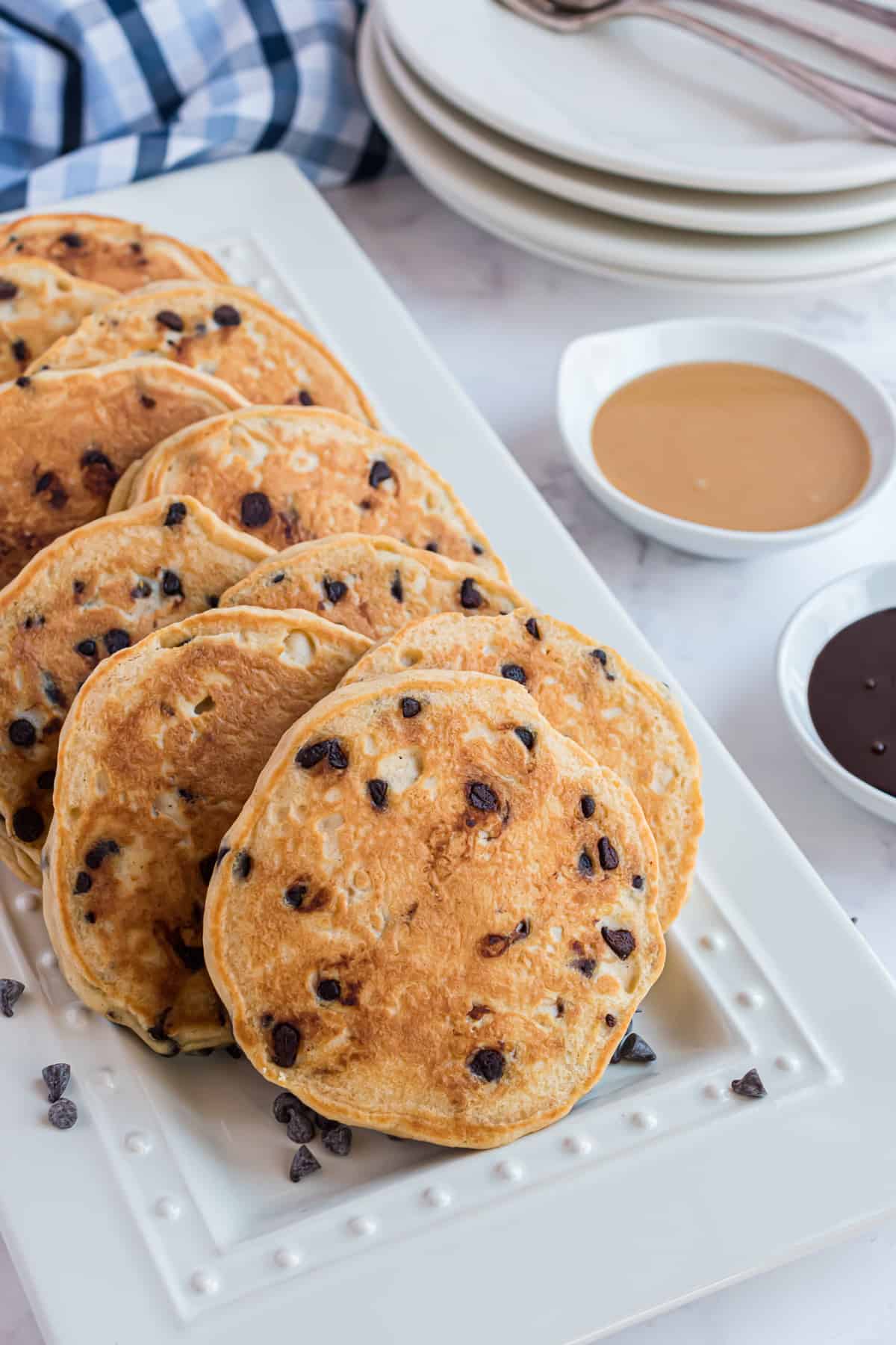 Pancakes parsemés de pépites de chocolat sur un plateau blanc.