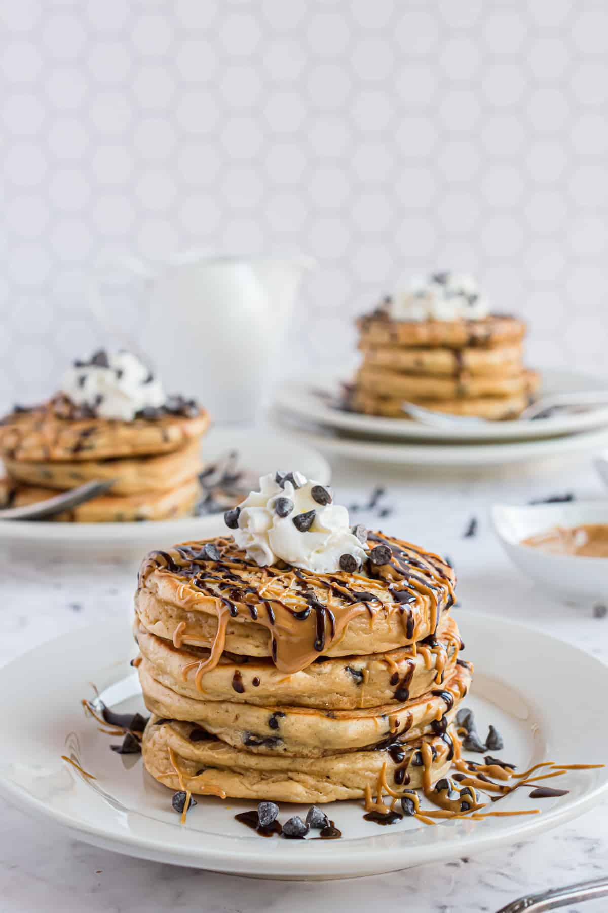 Trois assiettes de pancakes au beurre de cacahuète empilés.