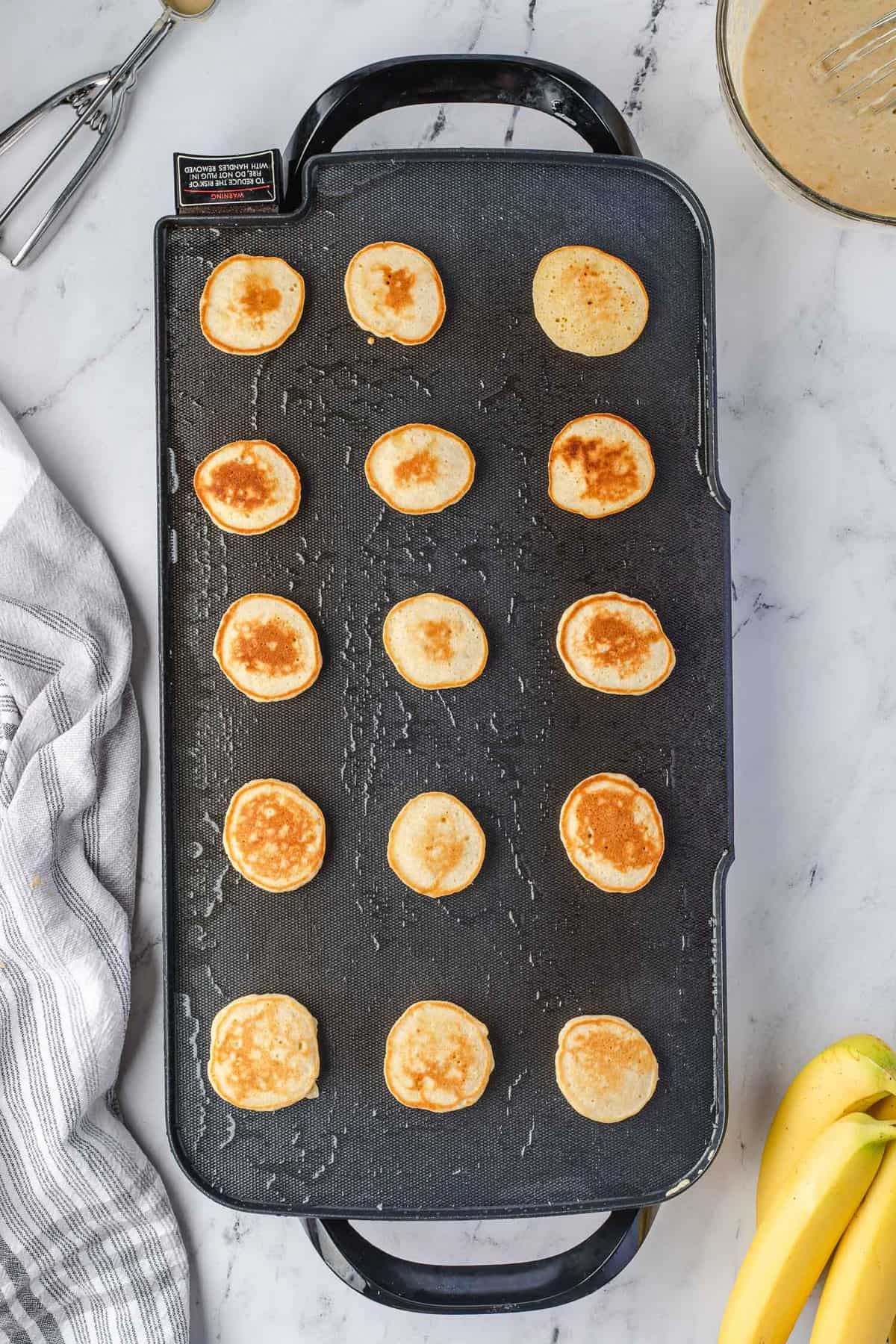 Pancakes cuits sur une grande crêpière.