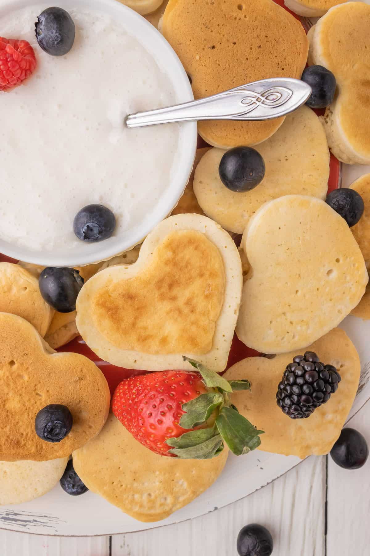 Pancake en forme de cœur à côté d'un bol de sauce au yaourt.