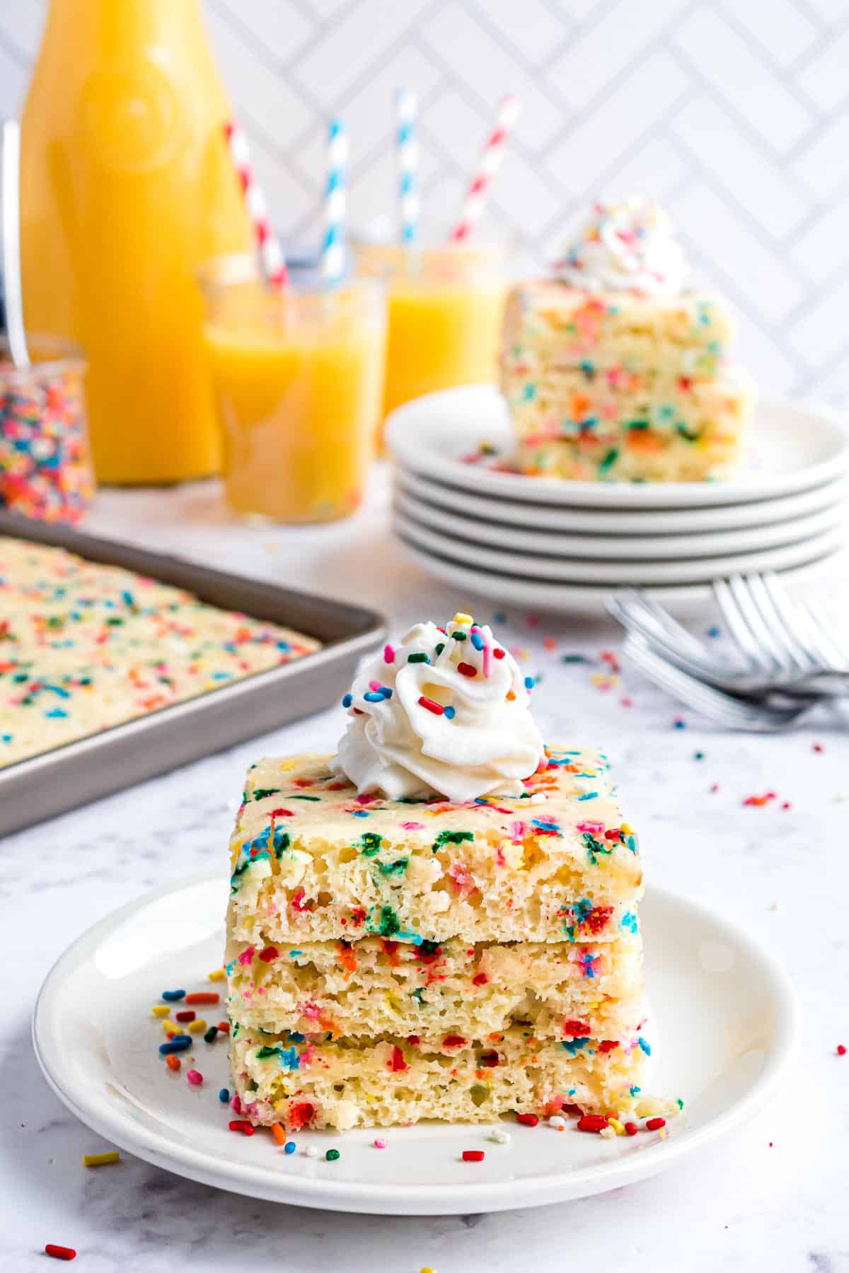 Du sirop versé sur une pile de pancakes garnis de confettis.