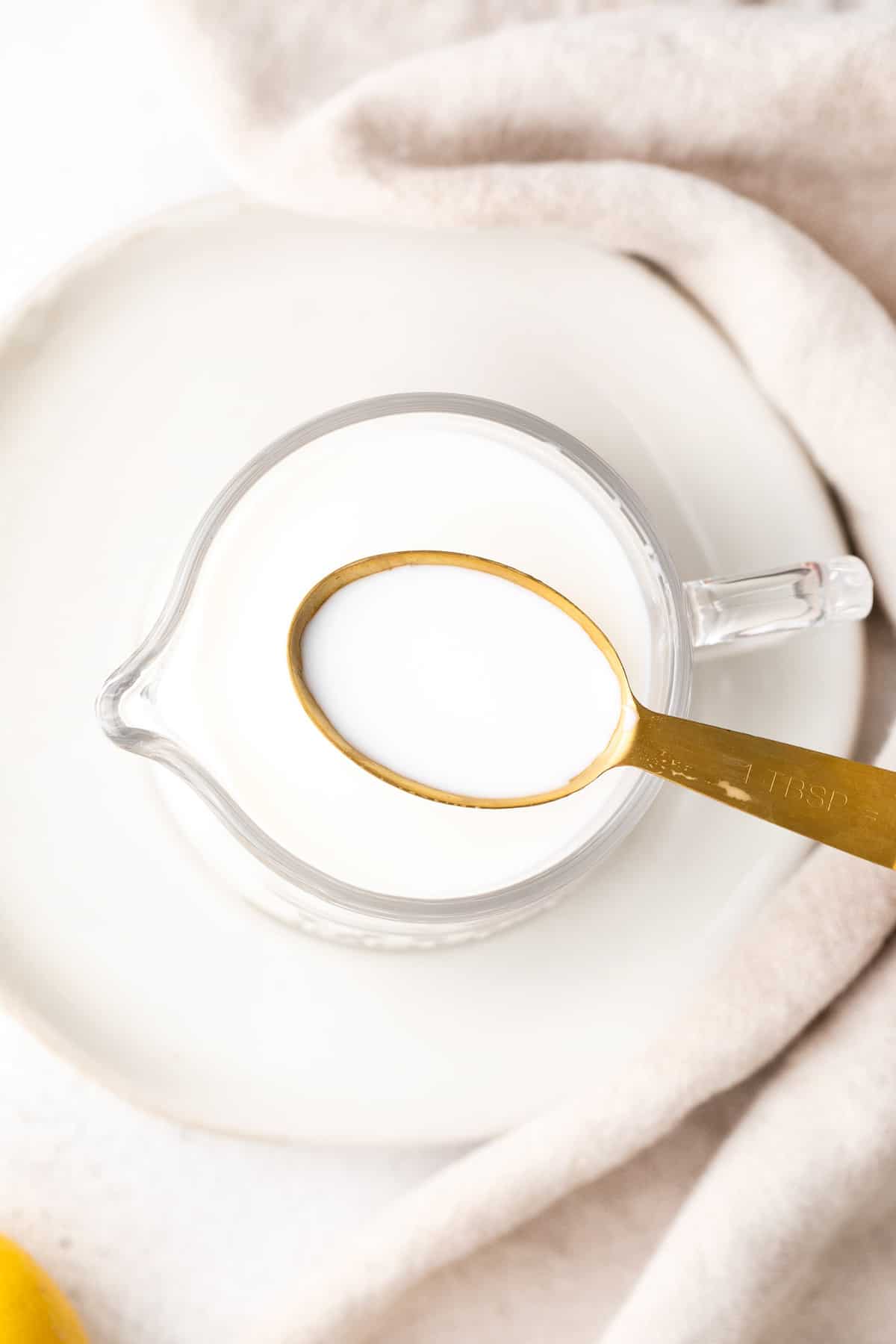Lait ribot sur une cuillère, au-dessus d'un pichet de lait.