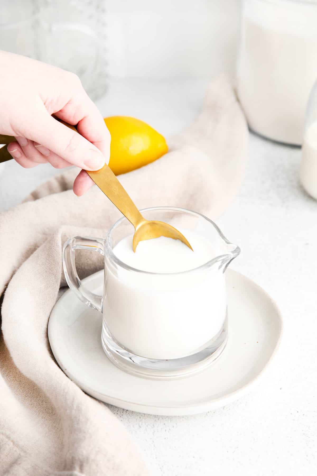 Cuillère de mesure plongée dans un petit pichet de lait.