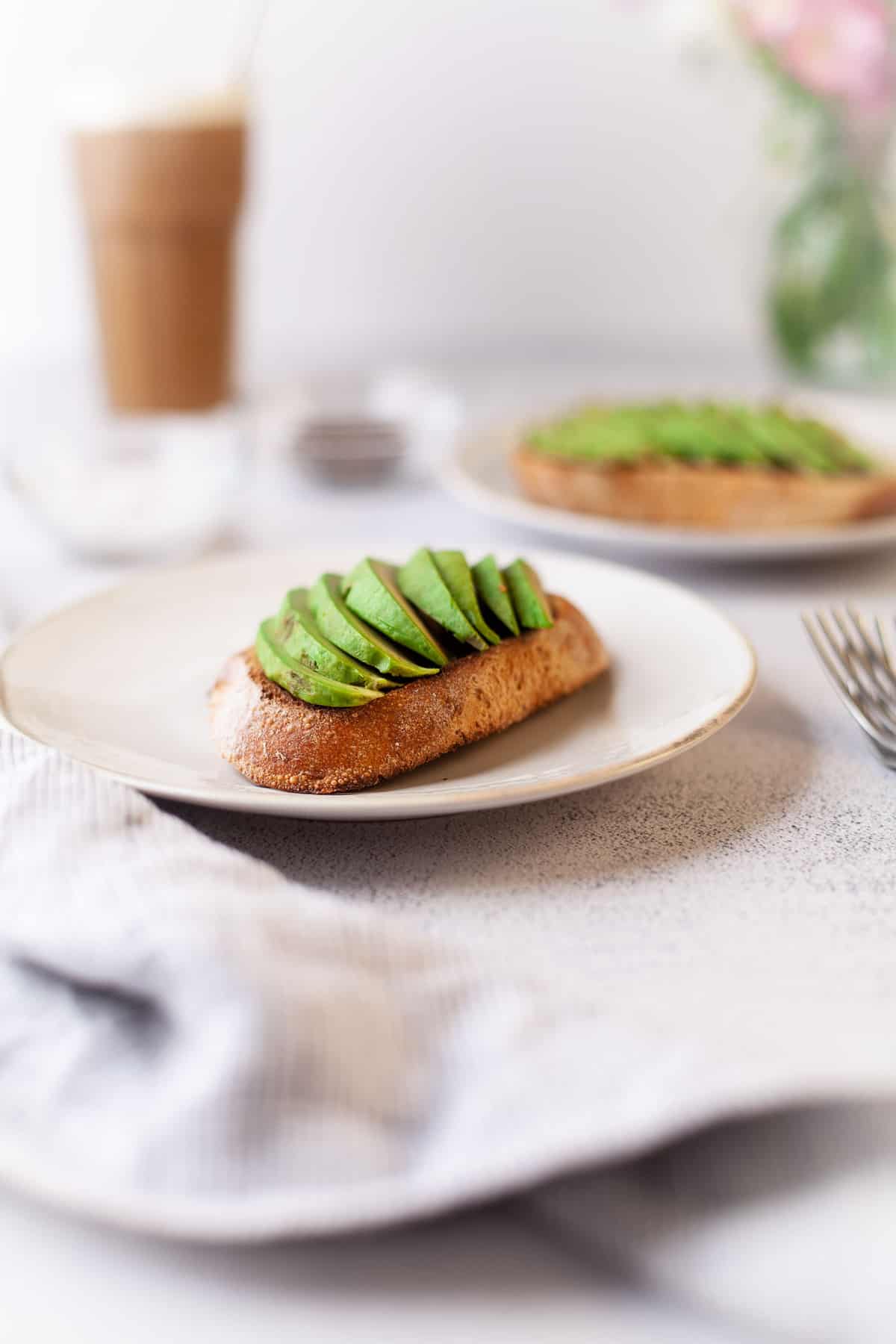 Tranches d’avocat sur une toast dans une assiette blanche.