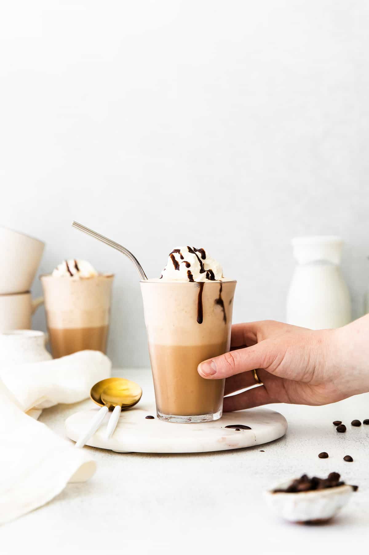Main prenant une boisson au café garnie de crème fouettée.
