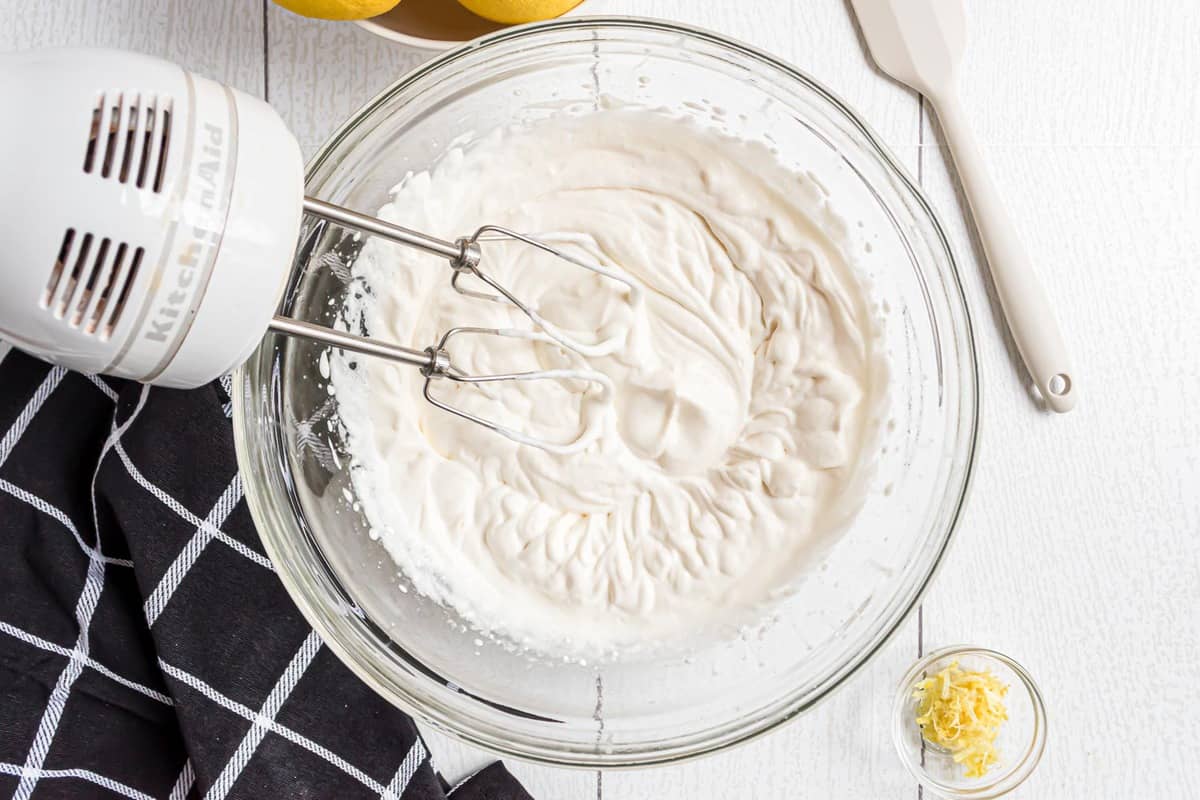 Crème fouettée battue dans un bol en verre transparent.