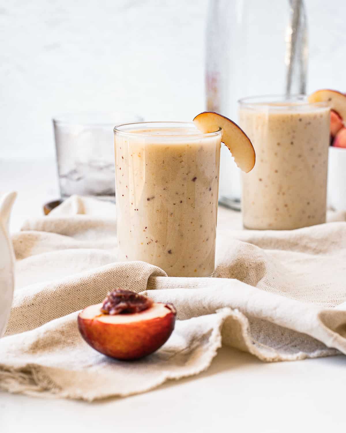 Deux smoothies de couleur orangée claire garnis de tranches de nectarine.