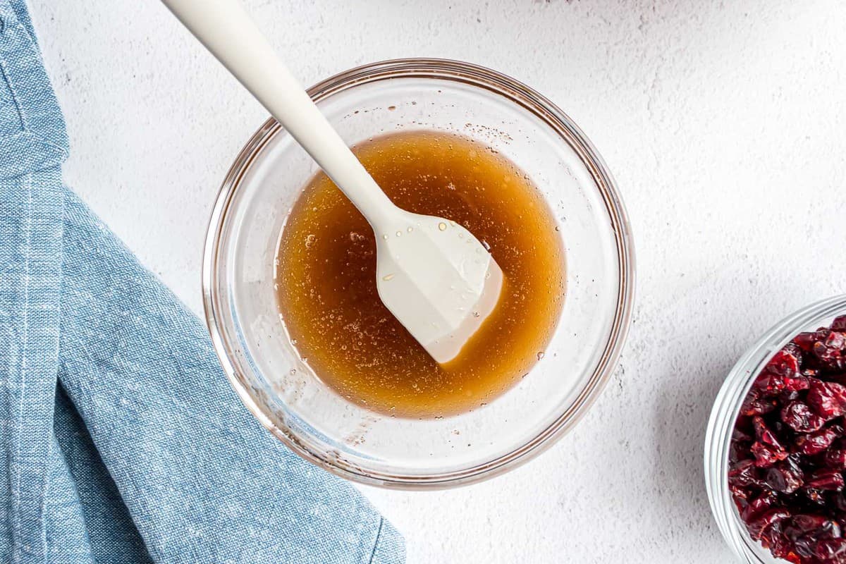 Ingrédients liquides pour le granola dans un bol en verre.