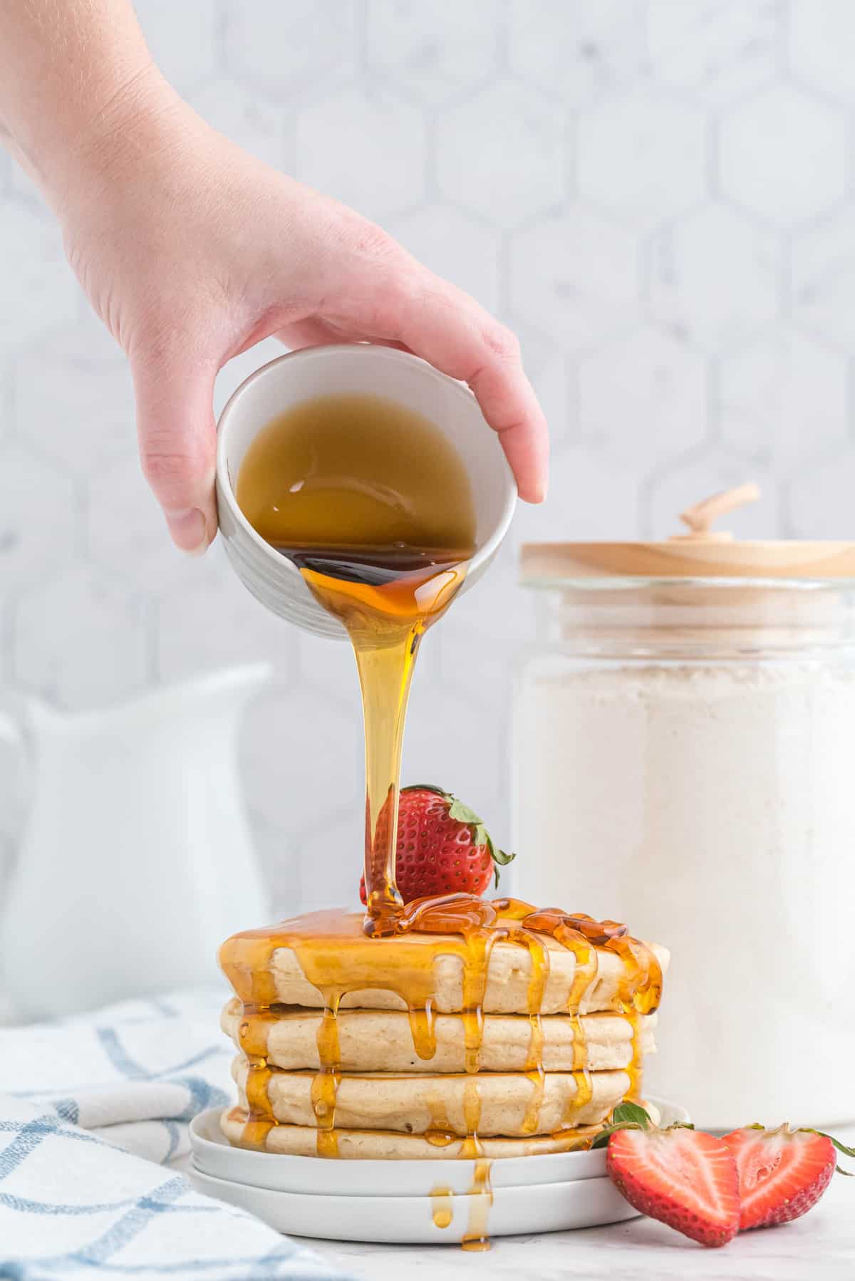 Du sirop versé sur une pile de pancakes.