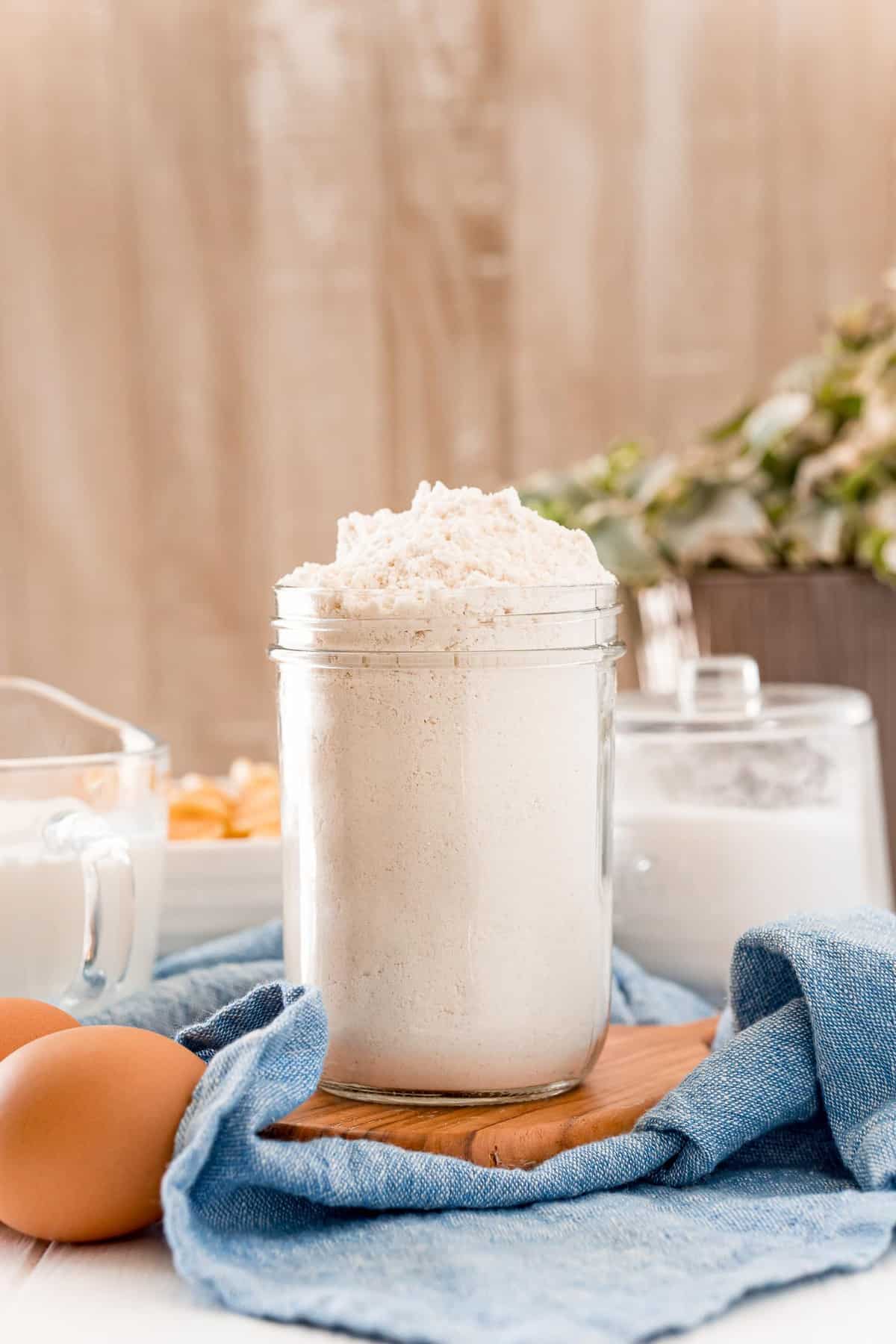 Pot de mélange Bisquick sur un plateau en bois, sur un linge bleu.