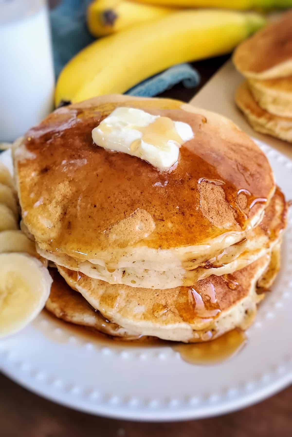 Pancakes avec une noisette de beurre sur le dessus, dégoulinant de sirop.