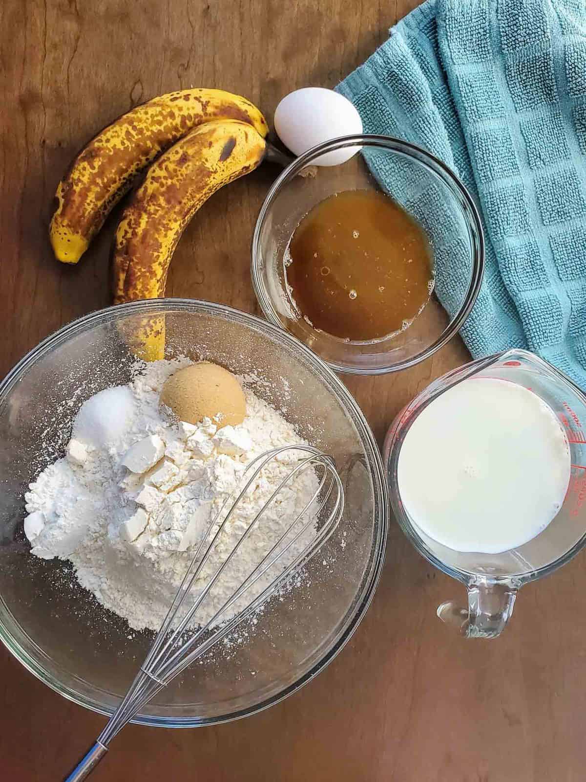 Vue aérienne des ingrédients : farine, œuf, sucre brun, banane, lait.