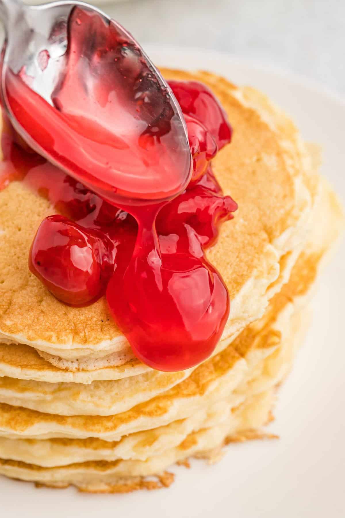 Garniture de tarte étant versée sur une haute pile de pancakes.