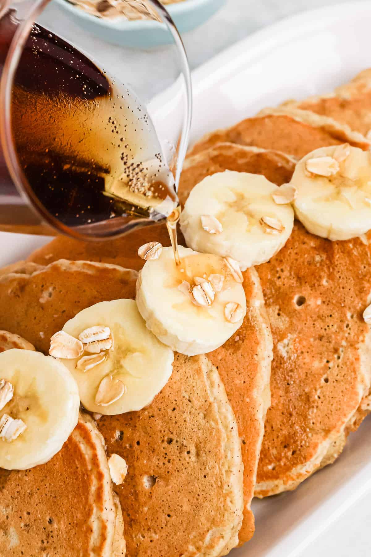 Du sirop étant versé sur des pancakes à la banane.