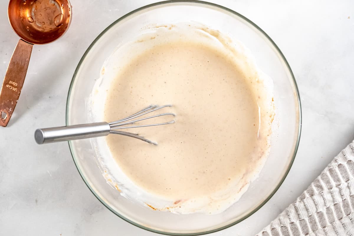 Mélange pour tremper le pain perdu vegan dans un bol de mélange en verre avec un fouet.