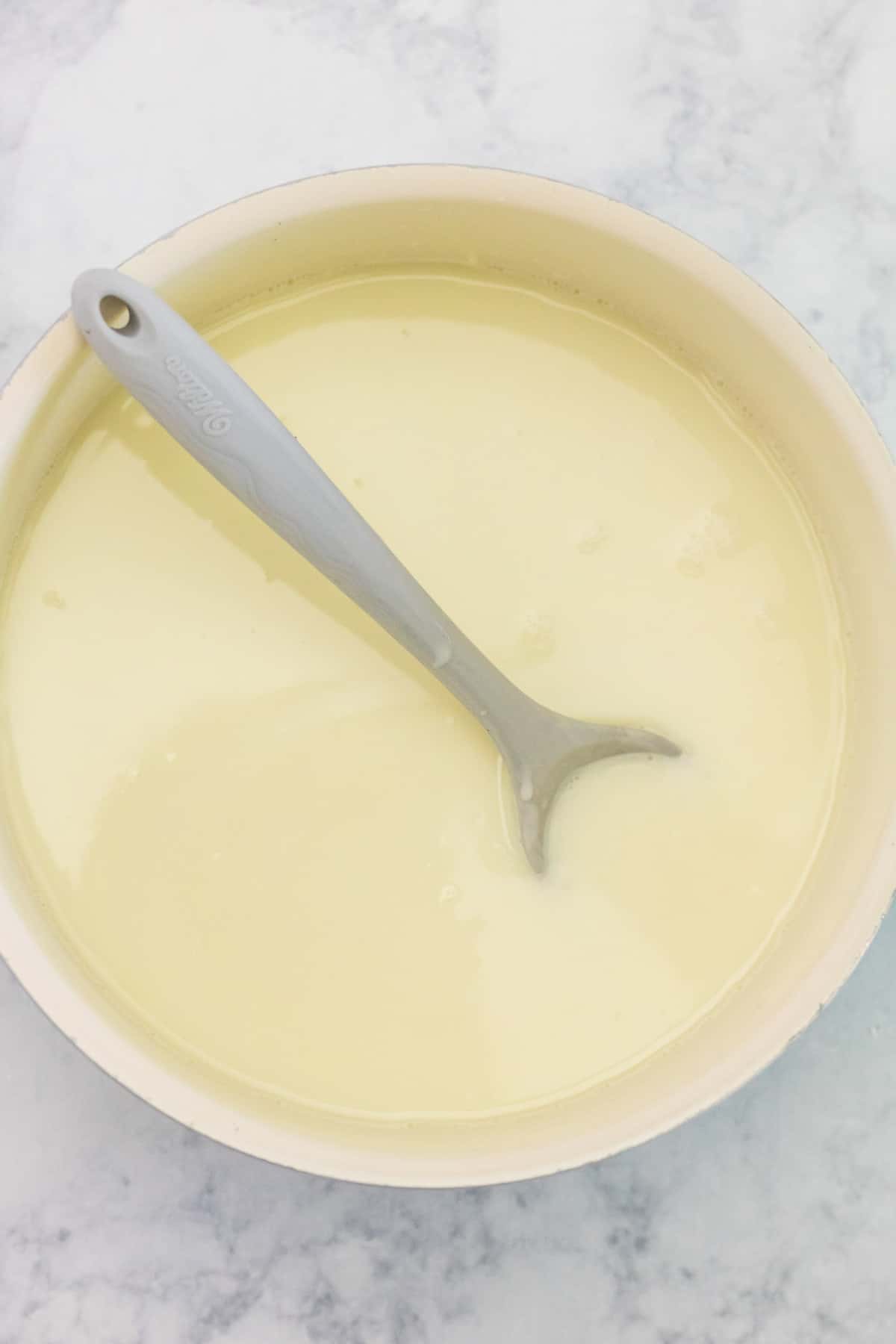 Chocolat chaud blanc dans une casserole avec une cuillère.