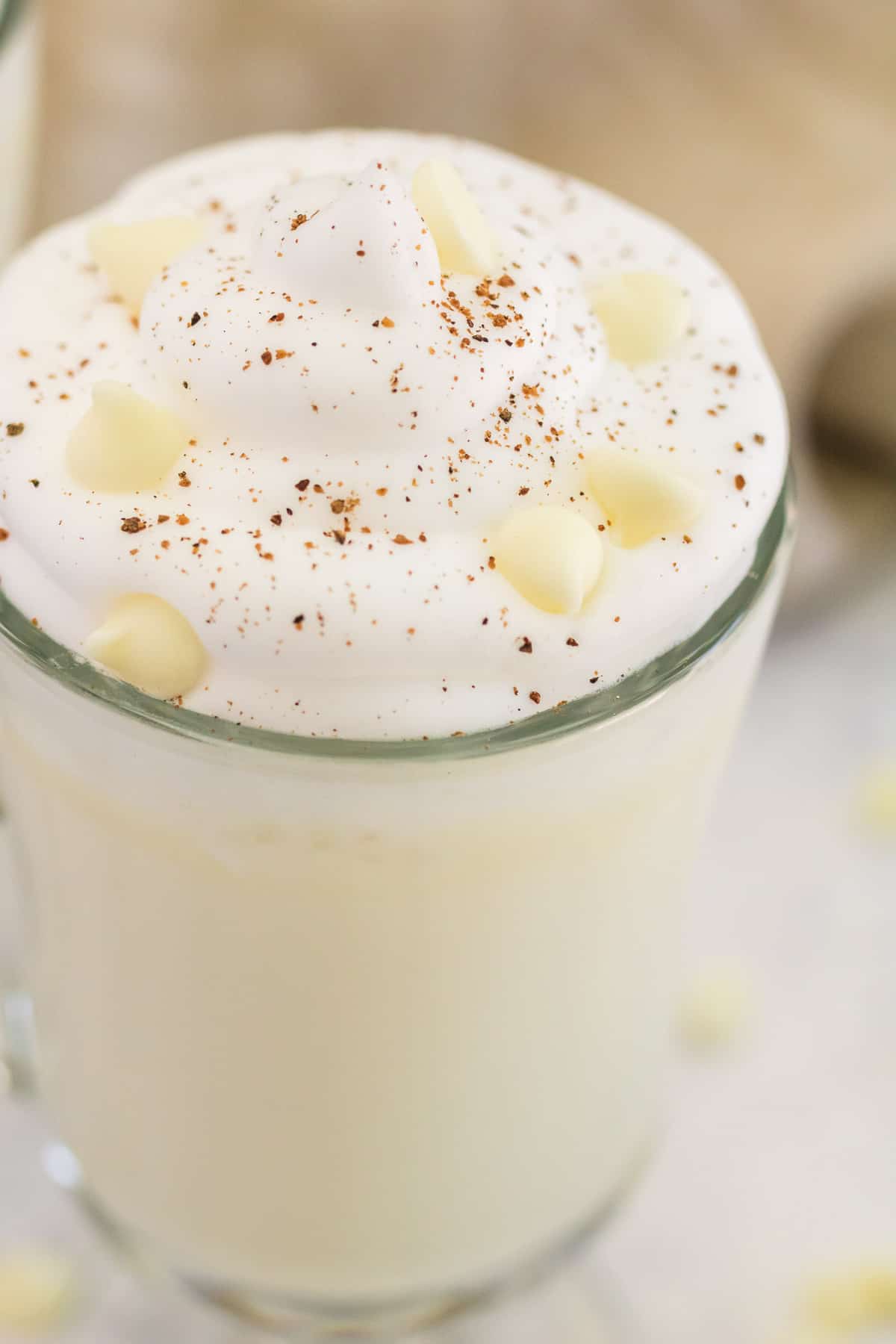 Gros plan sur du chocolat chaud blanc garni de pépites de chocolat blanc.