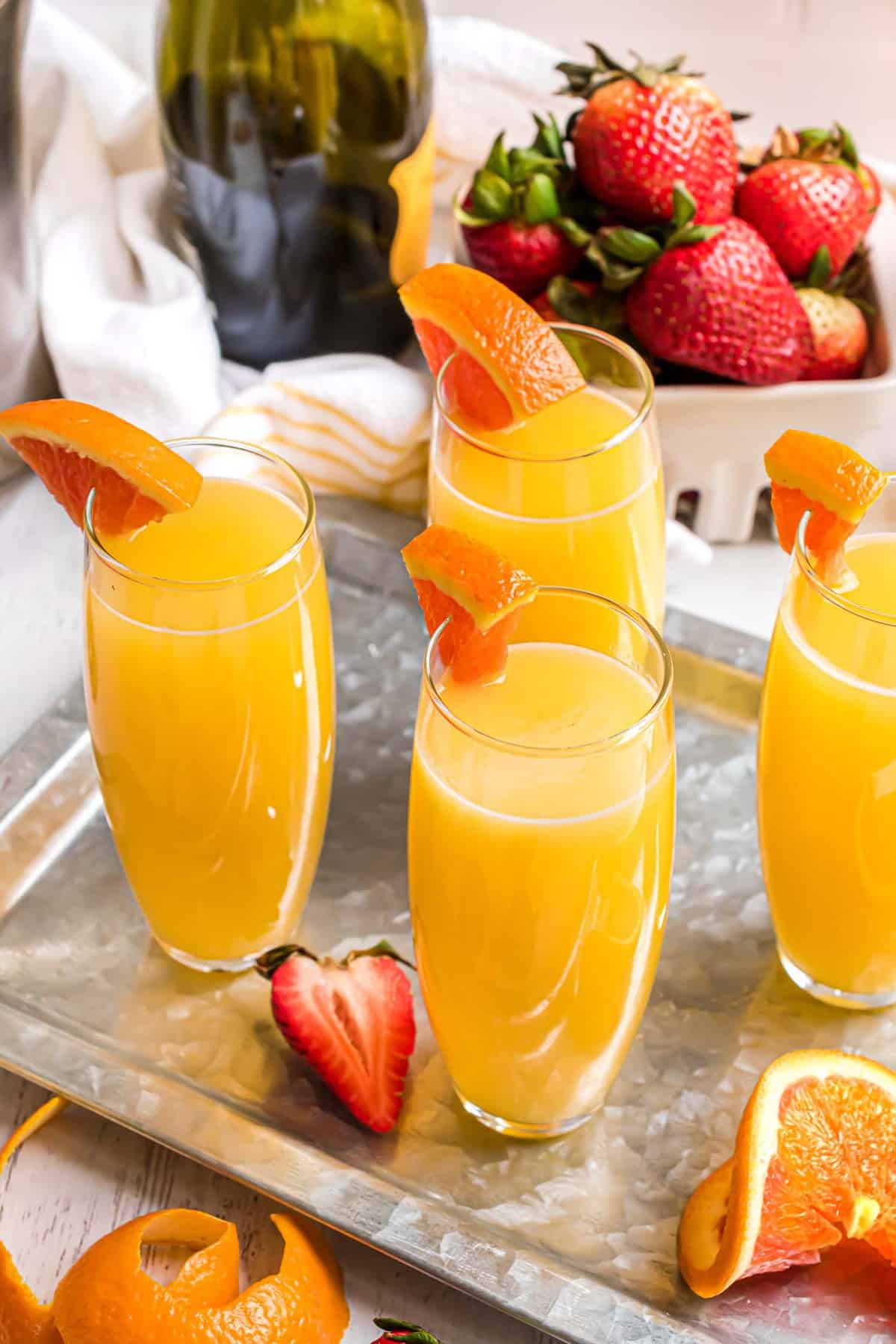 Plateau de cocktails mimosa avec du jus d'orange et un quartier d'orange en garniture.