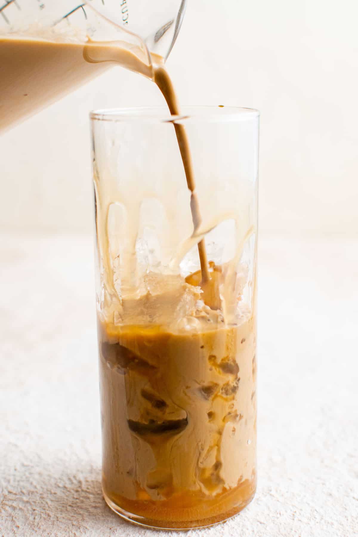 Latte versé sur de la glace dans un verre transparent haut.
