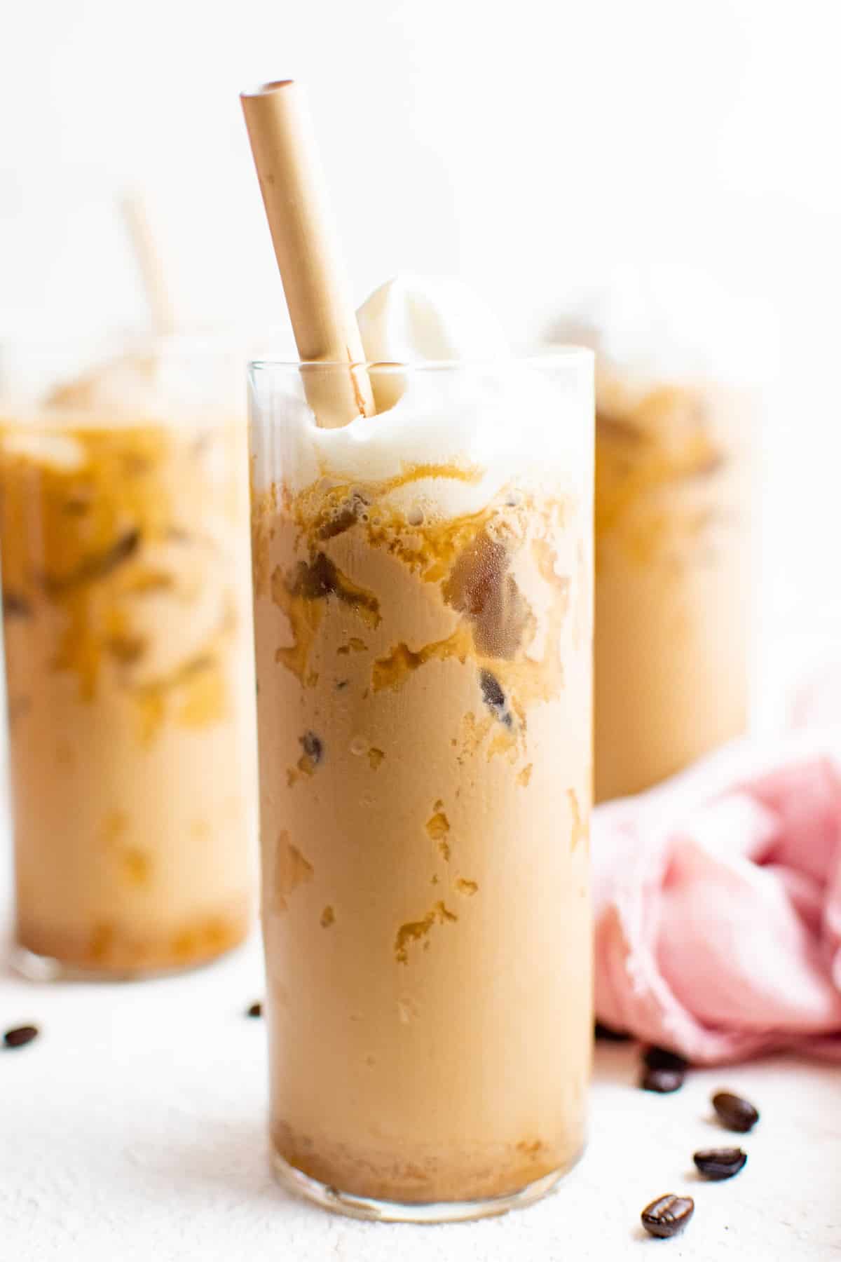 Latte glacé, surmonté de crème fouettée, dans un grand verre avec une paille brune.