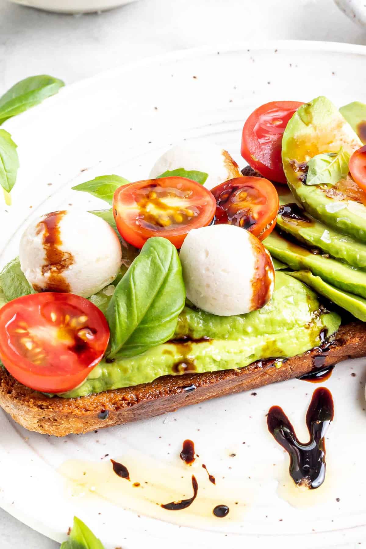 Gros plan sur le toast à l'avocat garni de salade caprese.