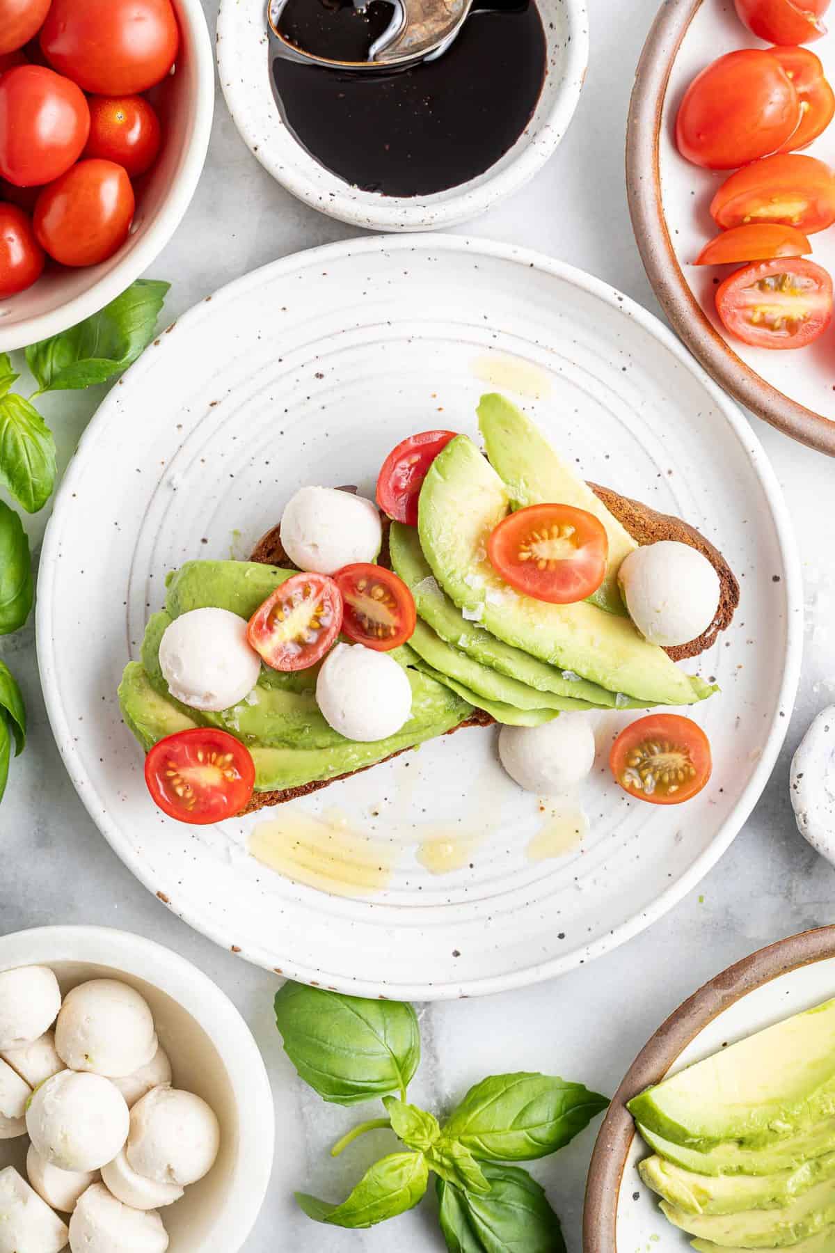 Toast à l'avocat garni de mozzarella fraîche et de tomates fraîches.