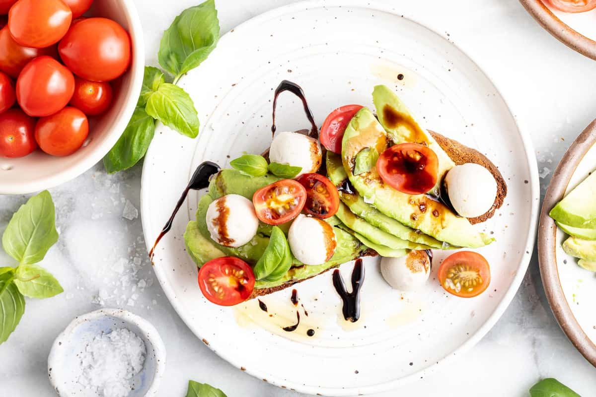 Toast garni d'avocat, de tomates, de mozzarella, de basilic et de balsamique.