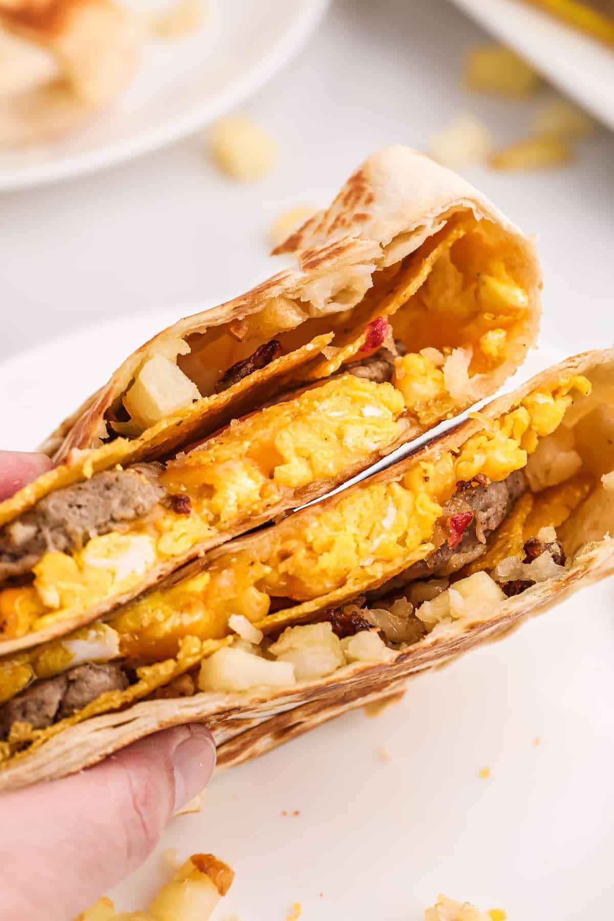 Main tenant deux moitiés d'un crunchwrap de petit-déjeuner.