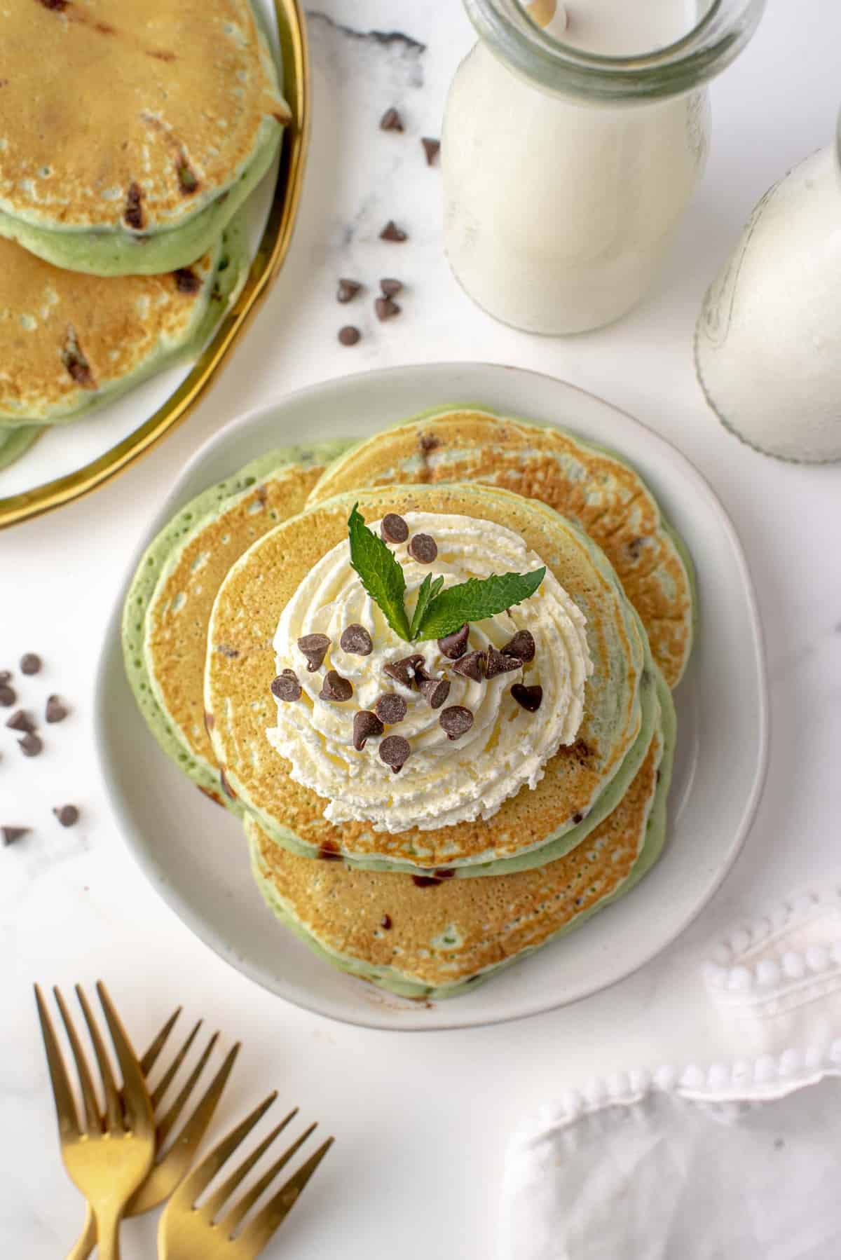 Assiette de pancakes à la menthe chocolatée avec crème fouettée et pépites de chocolat.