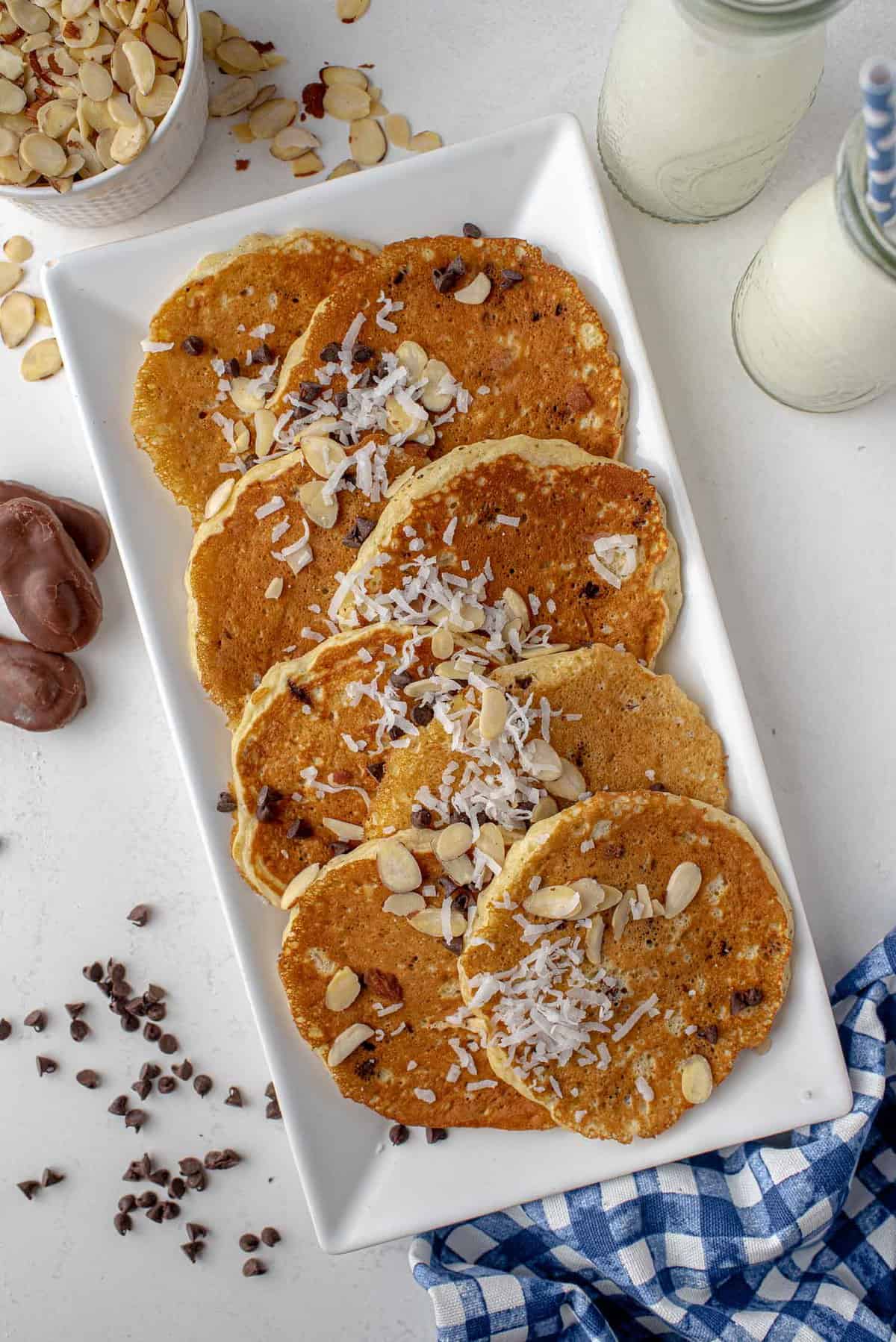 Pancakes almond joy sur un plateau saupoudrés de noix de coco et de pépites de chocolat miniatures.