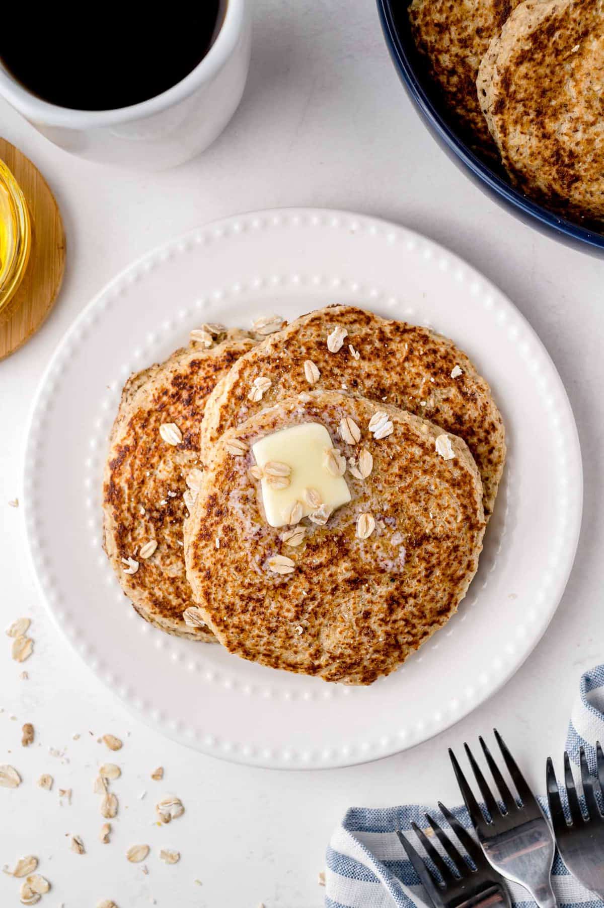 Trois pancakes garnis de beurre et de flocons d'avoine.