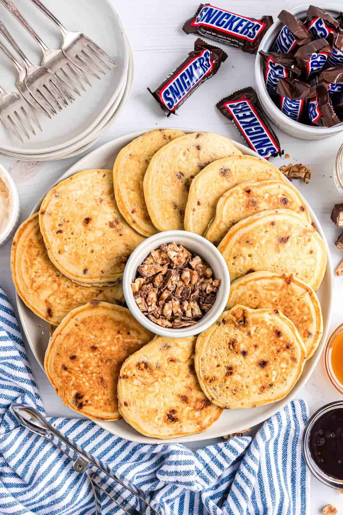 Pancakes présentés sur un plateau avec des garnitures à proximité.