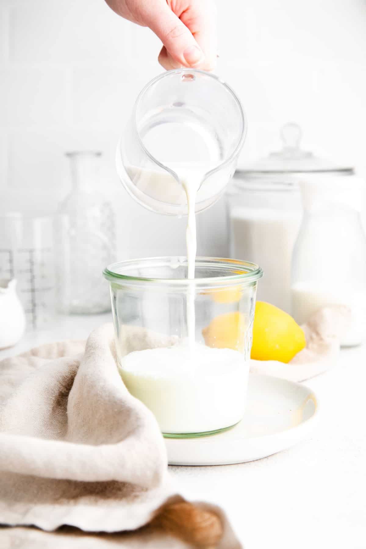 Lait ribot versé d'un petit pichet en verre dans un petit pot.