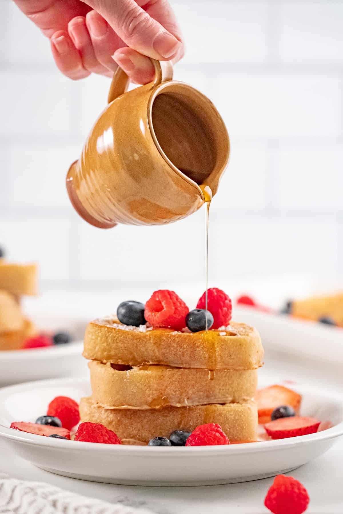 Du sirop versé sur une pile de pain perdu vegan.