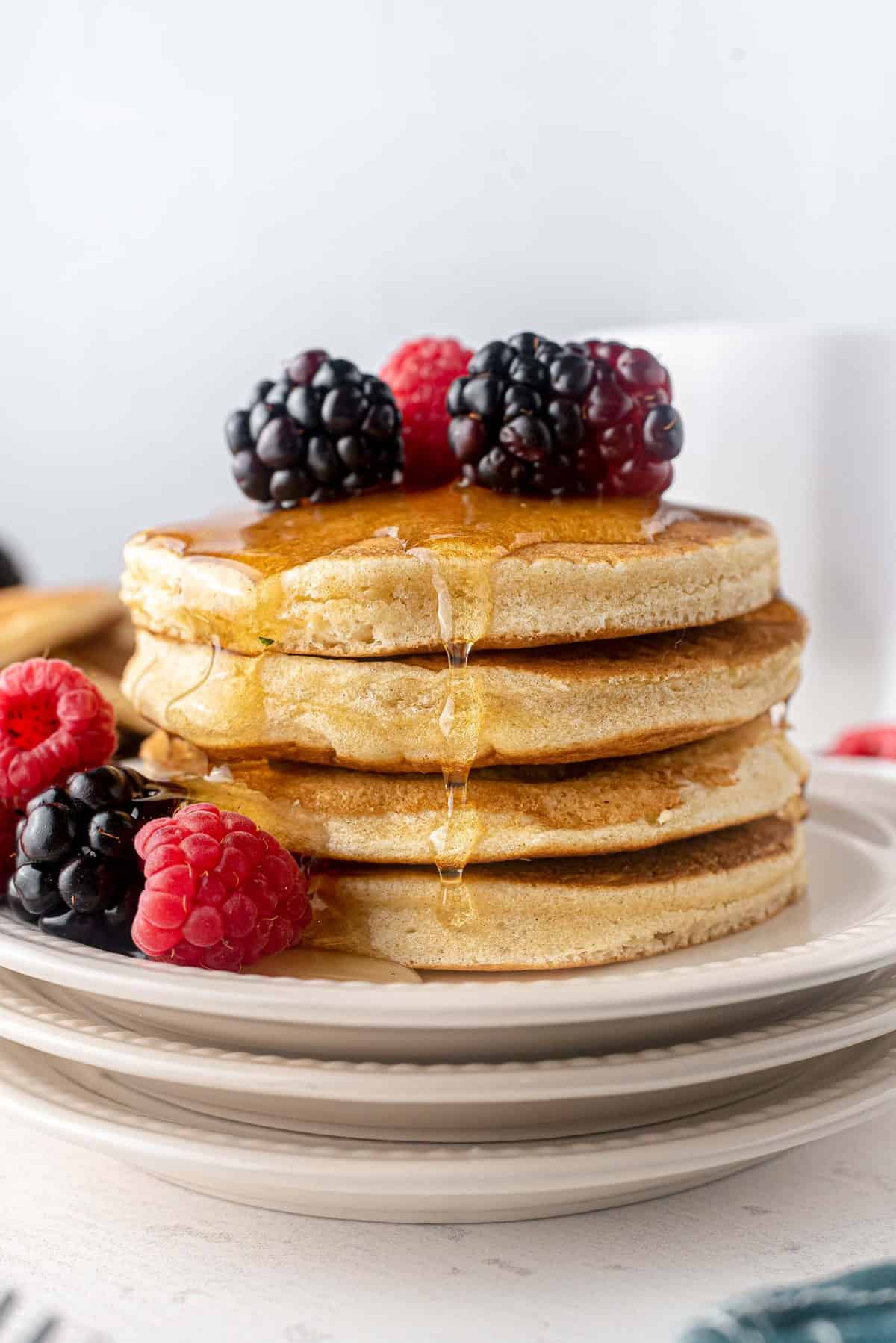 Pancakes moelleux sans produits laitiers avec du sirop et des fruits frais.