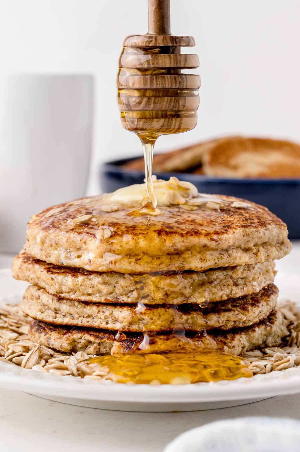 Du miel en train d'être versé sur des pancakes au miel et à l'avoine.