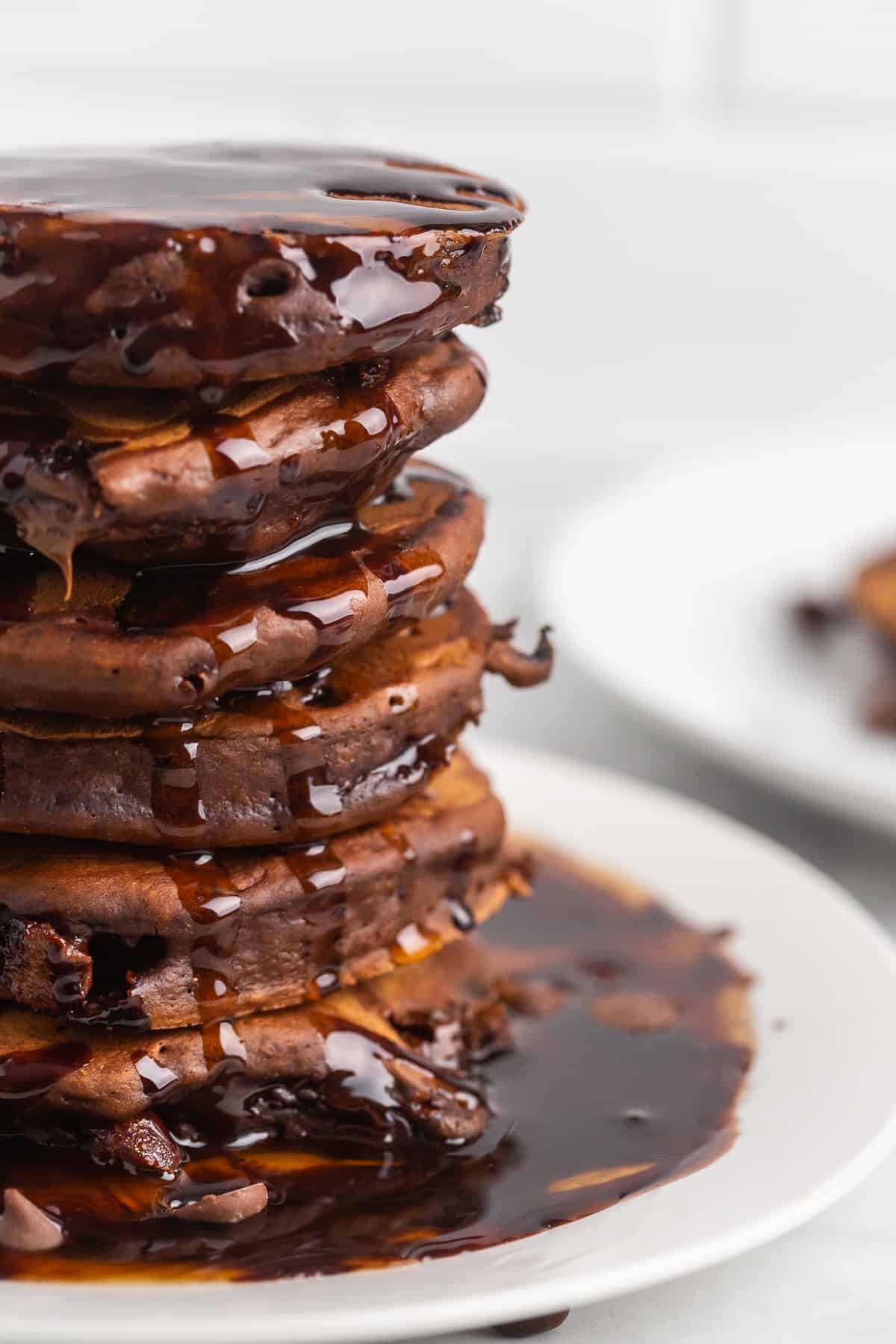 Gros plan d'une haute pile de pancakes au chocolat avec du sirop de chocolat.