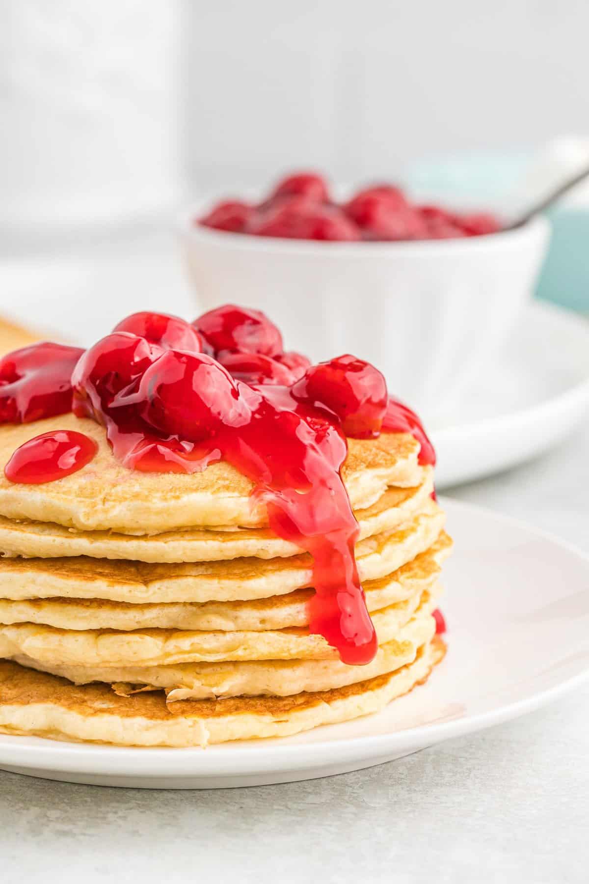 Empilement de pancakes aux cerises avec des cerises sur le dessus.